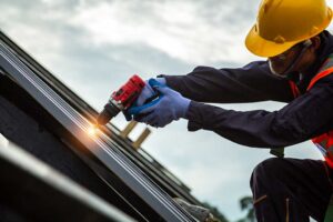 Homeowner inspecting a rain gutter and downspout beneath a shingled roof in autumn.