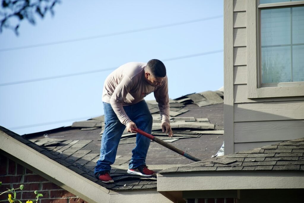 Homeowner examining roof shingles and gutters from the ground after a heavy storm.